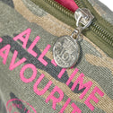 Detailaufnahme des Camouflage-Make-up-Täschchens mit pinker Aufschrift und münzförmigem Reißverschlussanhänger