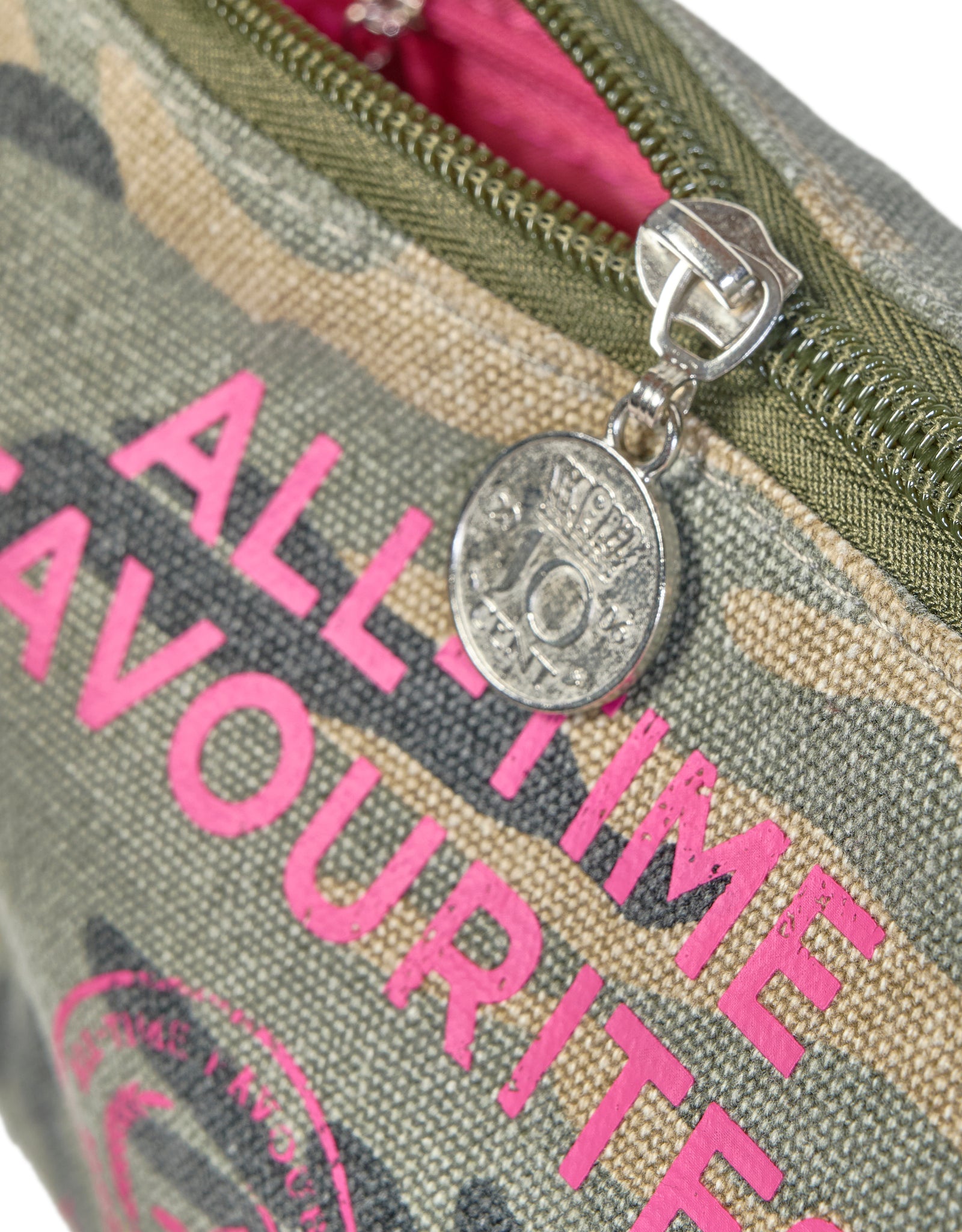 Detailaufnahme des Camouflage-Make-up-Täschchens mit pinker Aufschrift und münzförmigem Reißverschlussanhänger