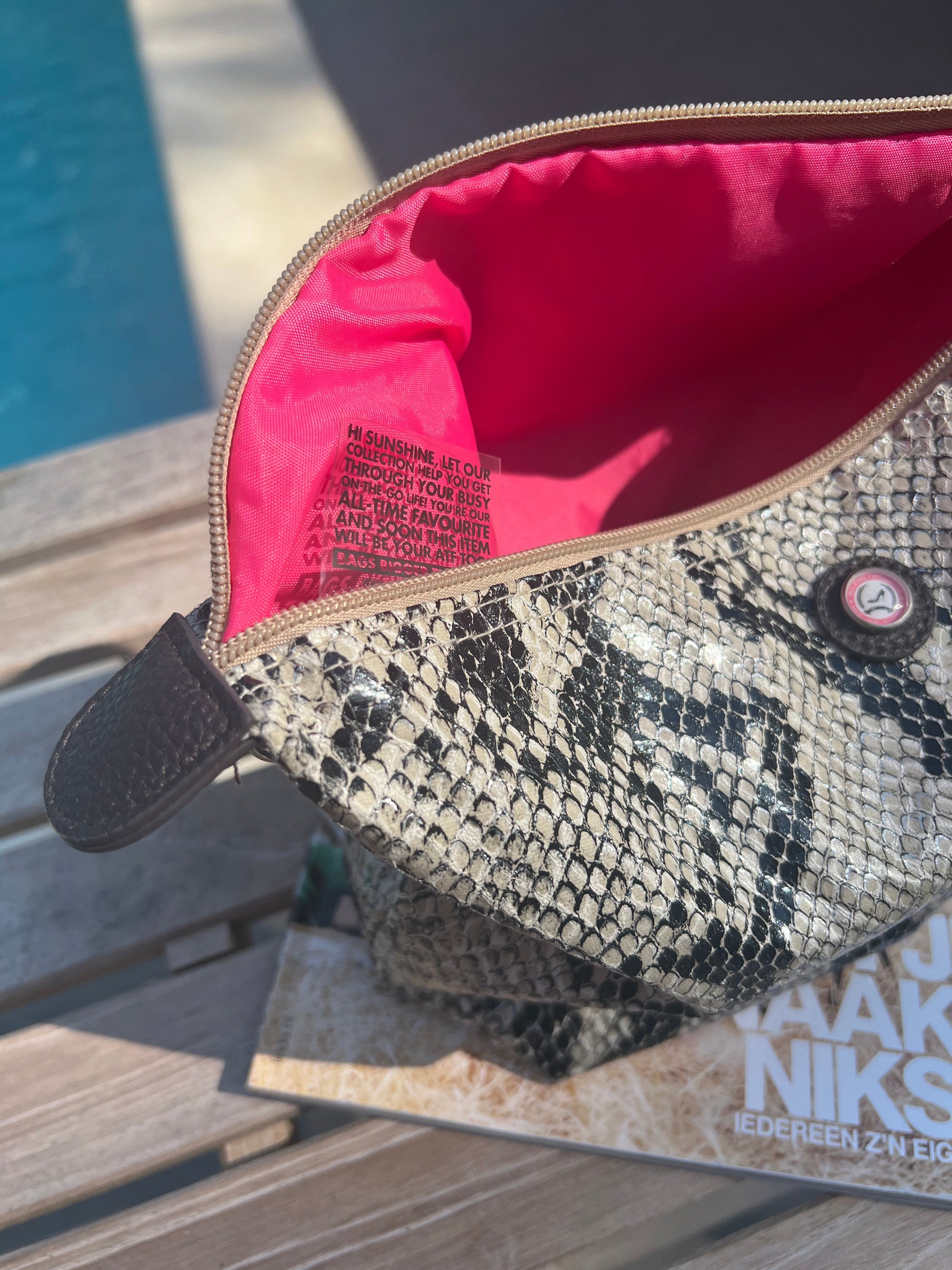 Close-up of python print toiletry bag with pink interior and practical zipper