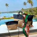 Tote bag and crossbody bag in black vegan leather and beige straw on a terrace with pool, palm trees and ocean view