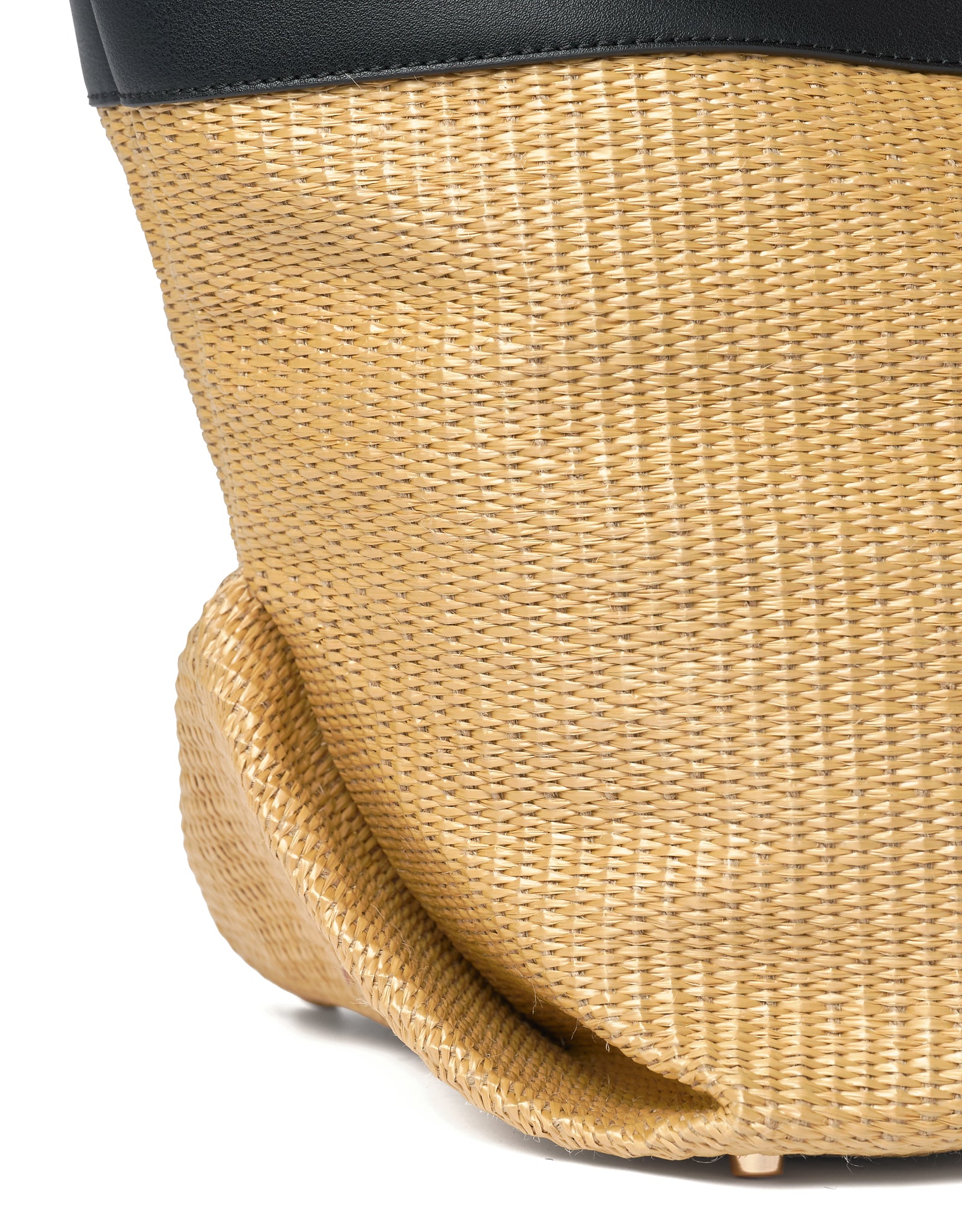 Close-up of a woven straw bag with protective metal studs