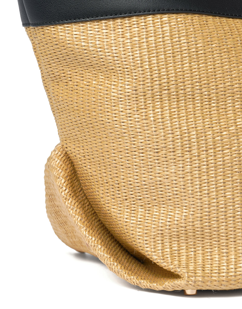 Close-up of a woven straw bag with protective metal studs