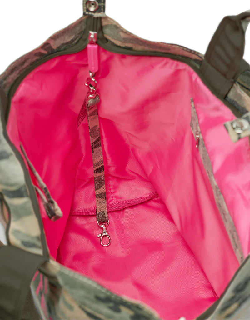 Middelgrote draagtas met camouflagepatroon aan de buitenkant, roze voering, binnenvak en een riem met camouflagepatroon en metalen sluiting.