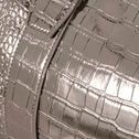 Close-up of a metallic silver bronze handbag with crocodile texture.