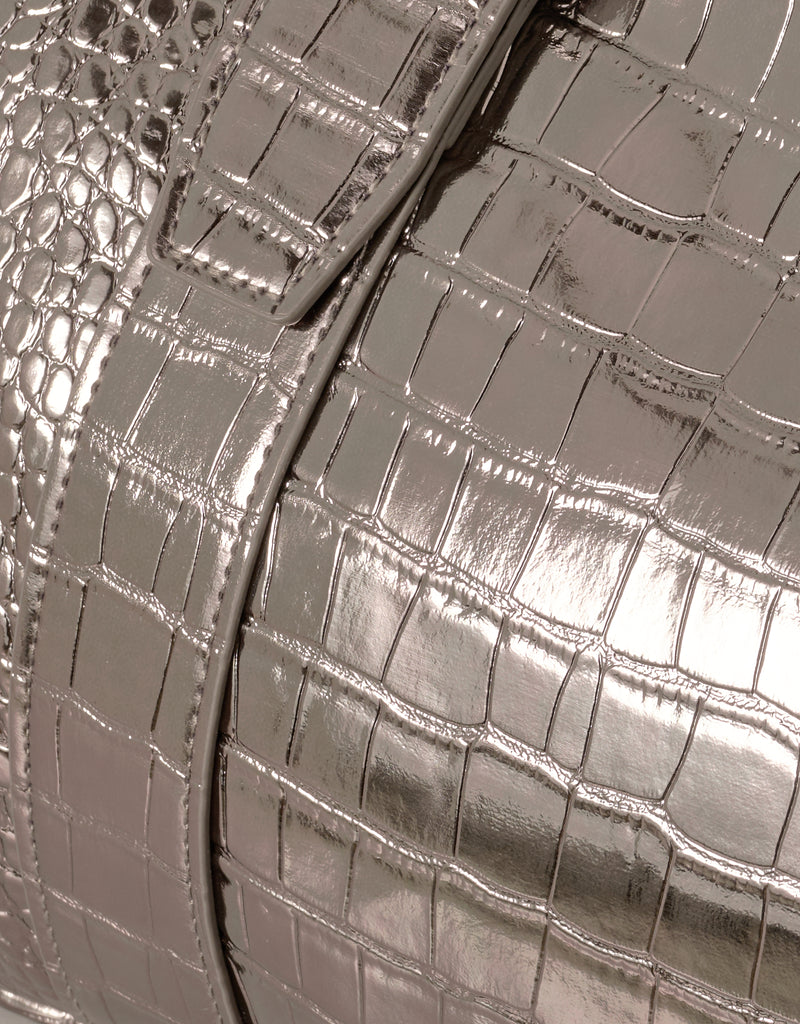 Close-up of a metallic bronze gold handbag with crocodile texture.