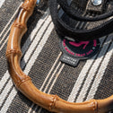 Brown bamboo handle with a black strap and pink All-time Favourites logo on a textured surface