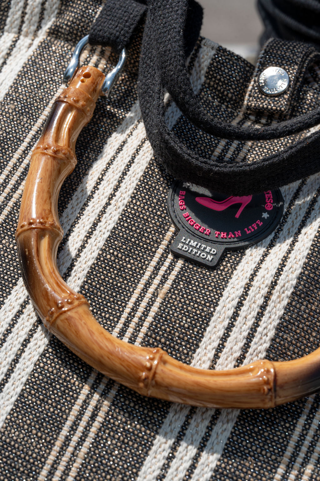 Brown bamboo handle with a black strap and pink All-time Favourites logo on a textured surface