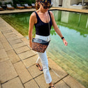 Woman walking by a poolside with a small leopard print crossbody bag