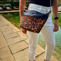 Woman wearing a leopard crossbody bag with gold chain walking by a resort pool