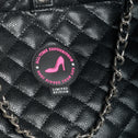 Black quilted handbag with a chain detail and a label on a black background