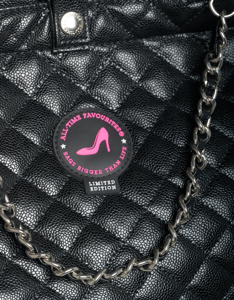 Black quilted handbag with a chain detail and a label on a black background