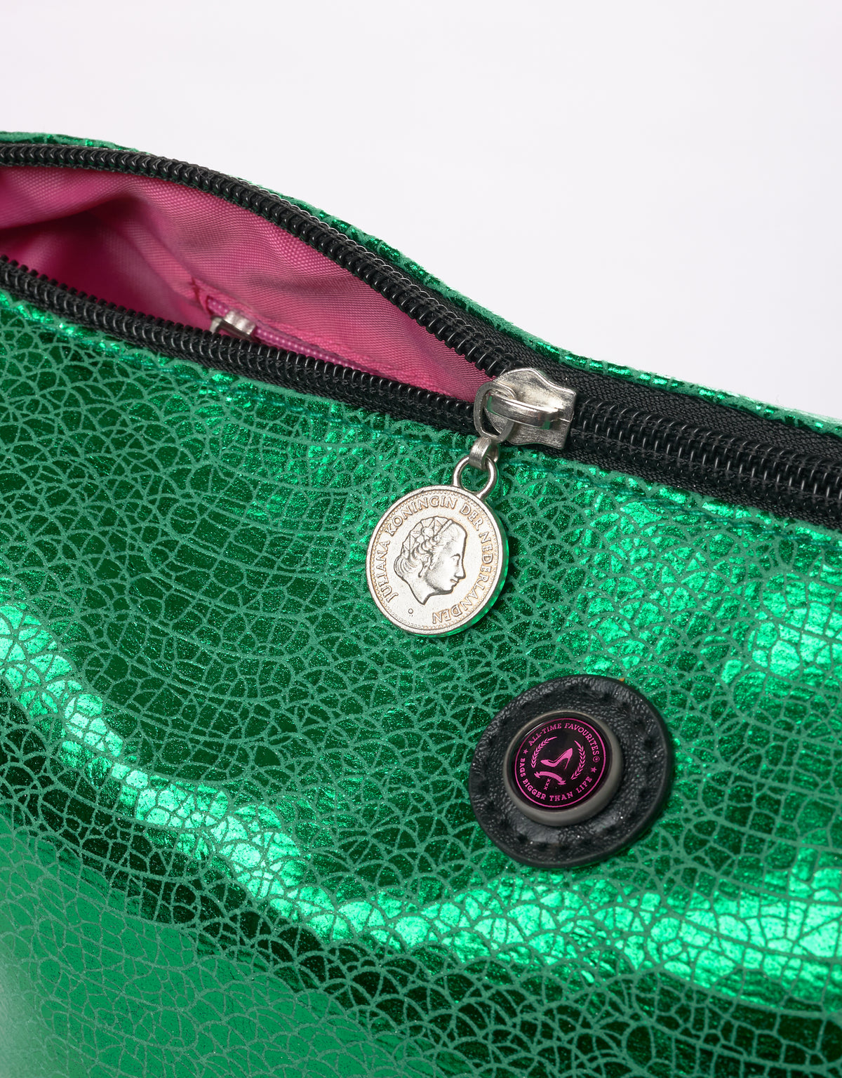 Metallicgroene VENEZIA-toilettas met roze voering, ritssluiting met muntvormig trekkertje en sluiting met ronde knoop.
