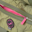 Green nylon puffer bag with pink zipper, pink lining and a patch on the front.