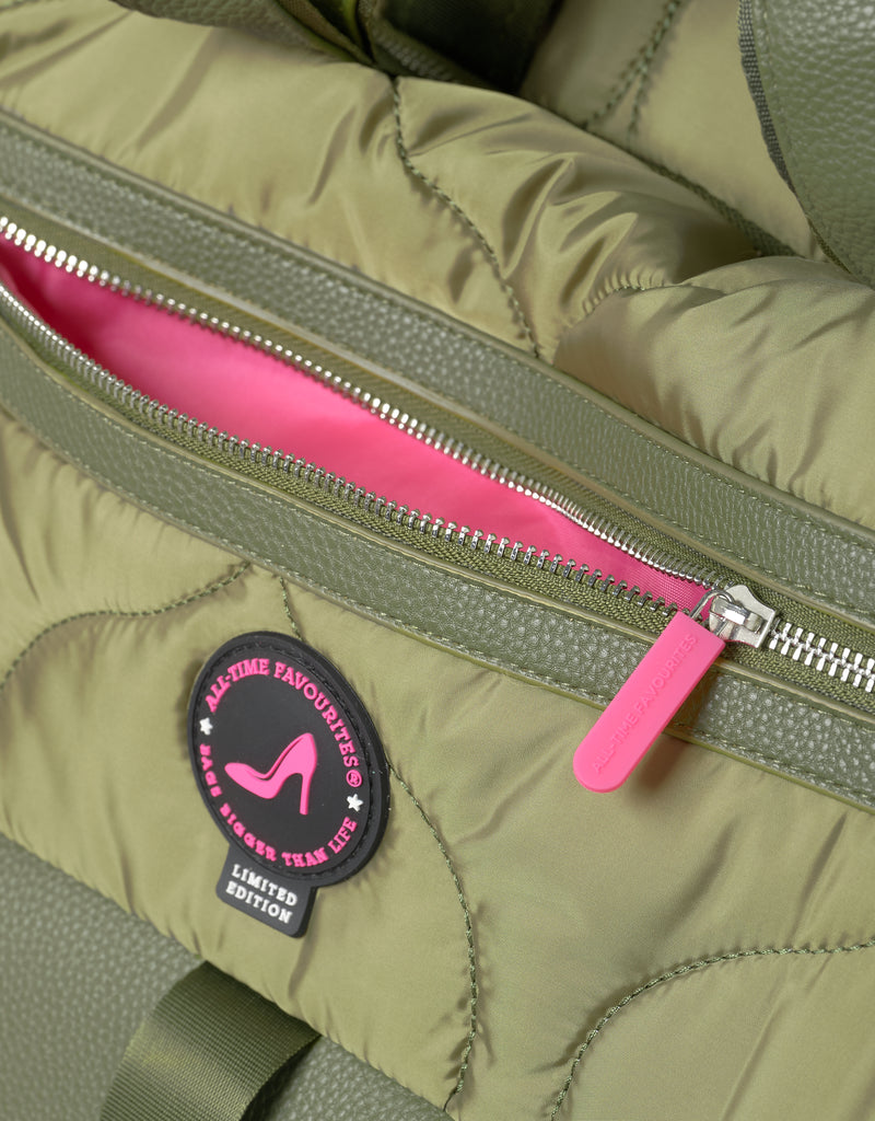 Close up of green puffer bag with pink zipper, pink lining and a brand patch saying limited edition