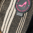Close-up of a black and white striped tote bag with a 'All-Time Favourites' patch featuring a pink high heel design.