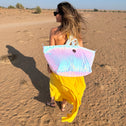 Woman in a yellow dress showing a colorful sequin large tote bag in a desert setting