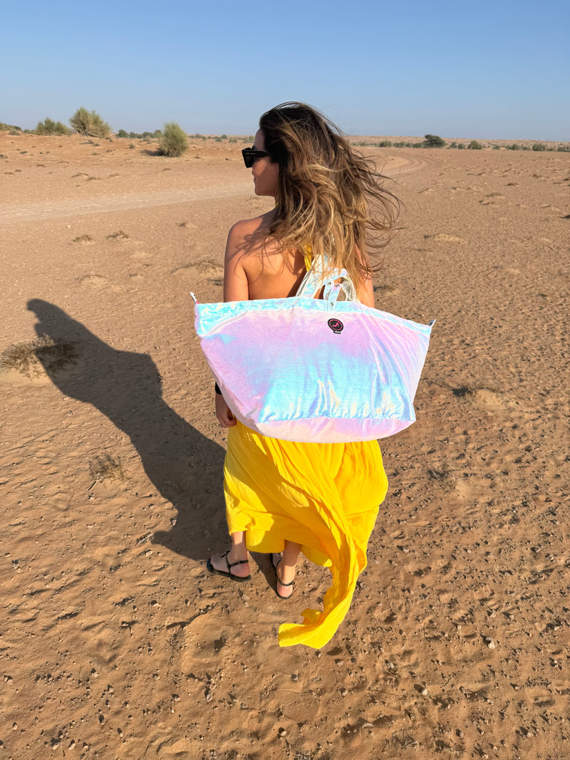 Woman in a yellow dress showing a colorful sequin large tote bag in a desert setting