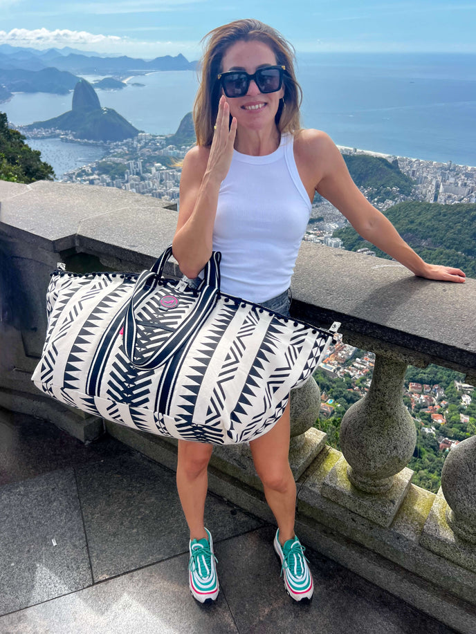 Woman carrying the Rio Large Tote Bag with black and white geometric pattern, zipper closure and front pocket, at a scenic viewpoint in Rio de Janeiro.