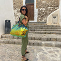 Woman standing in front of old house wearing a green gold colorod aequin bag
