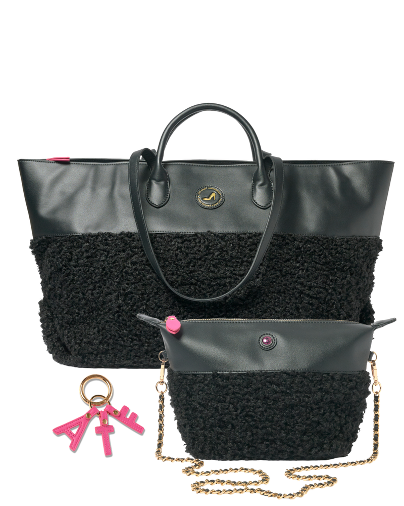 A black tote bag with a textured sherpa-style lower half, dual top handles, a small matching pouch with a gold chain strap, and a pink keychain charm, shown on a plain white background.