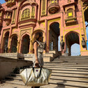 Person holding a large bag in front of a pink palace with intricate architecture