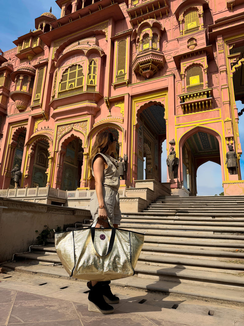 Person holding a large bag in front of a pink palace with intricate architecture