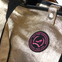 Detail of Jaipur Tote Bag with champagne gold coated cotton, black webbing handles and round All-time Favourites logo