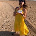 Woman in a yellow dress standing in the dessert showing a small mermaid coloured key pouch