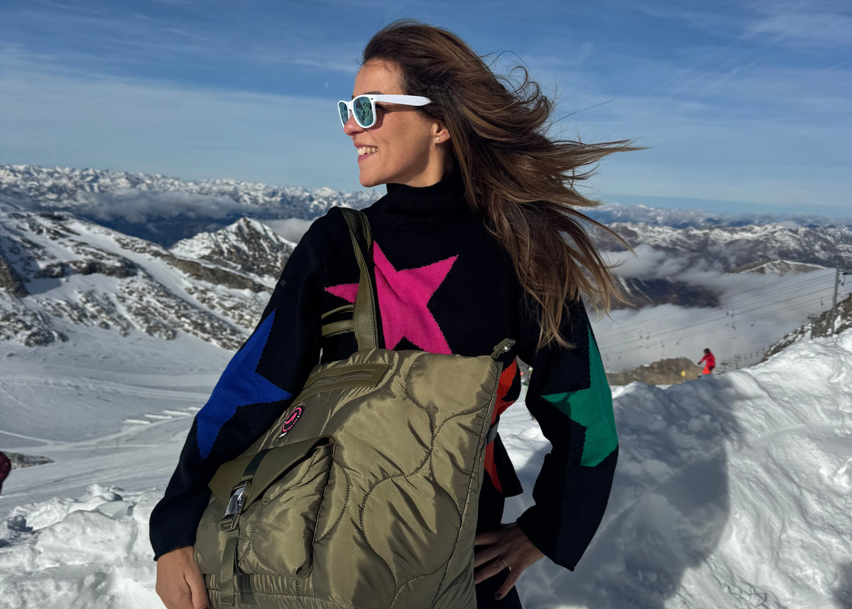 Woman in sunglasses on snowy mountain with wool star sweater and black leather All-time Favourites DIANA tote bag.