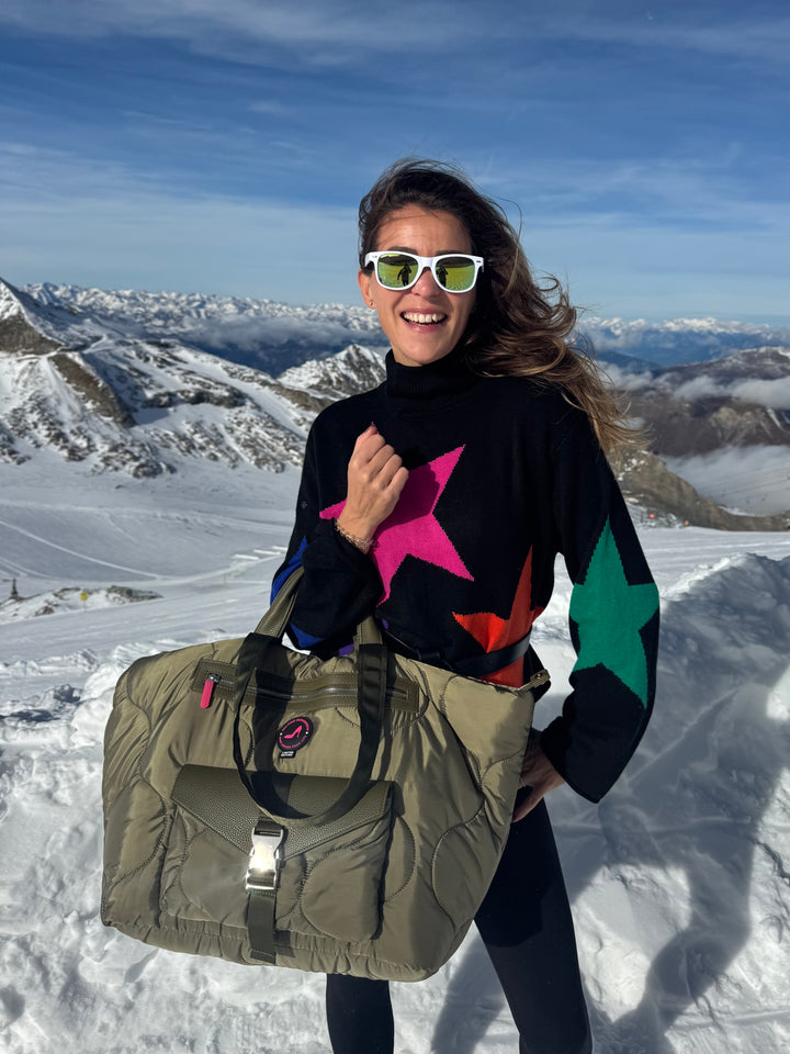 Woman with sunglasses holds Puffy Green DIANA All-time Favourites Medium Tote Bag on snowy mountain.