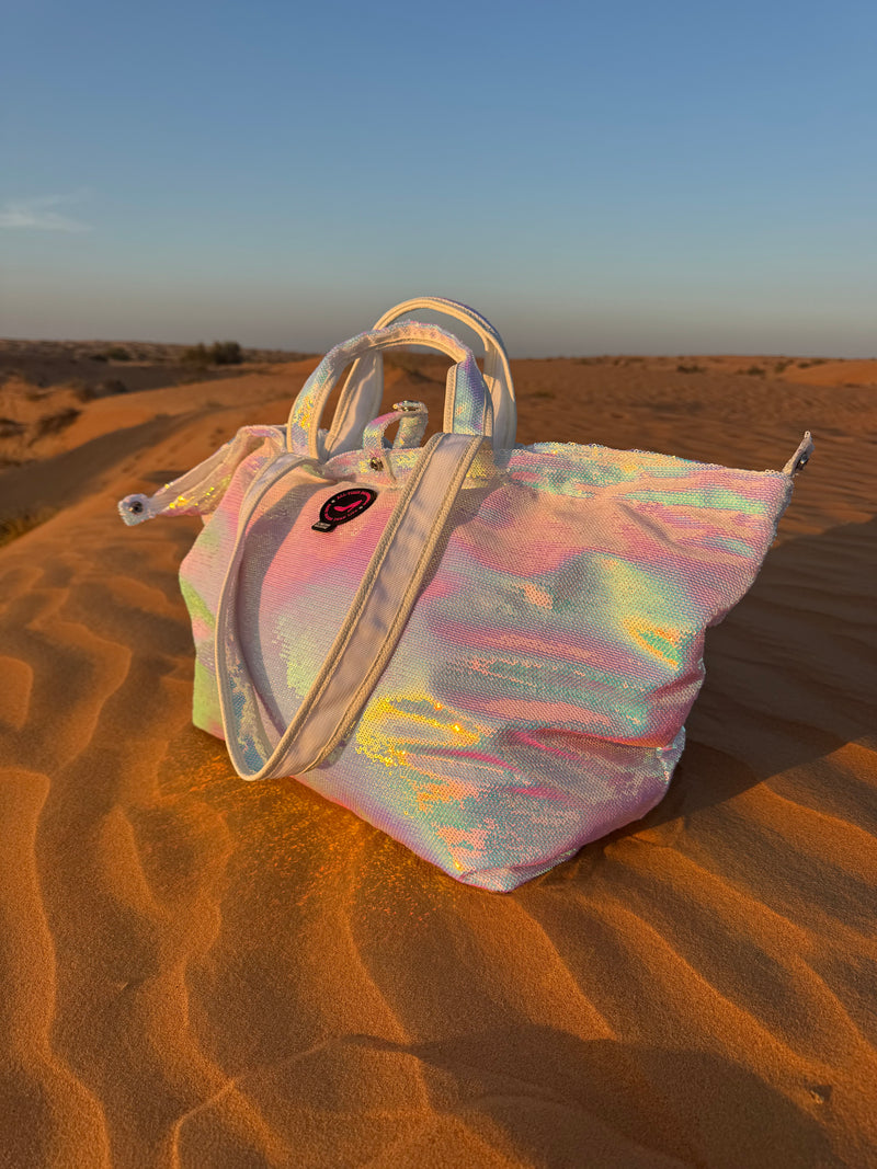 Iridescent large tote bag on a sand dune in the desert with a blurred background.”