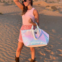 Woman in a desert setting holding a iridescent tote bag