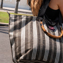 Person holding a black and white striped All-time Favourites bag with a blurred background