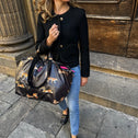 Woman carrying a large bag with animal prints on a city street.