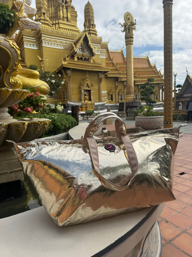 Large gold metallic python print tote bag photographed in front of a Thai temple