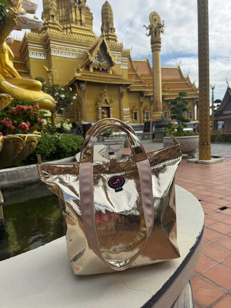 Small gold metallic python print tote bag photographed in front of a traditional Thai temple