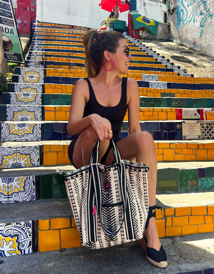 Woman sitting on Selarón Steps in Rio de Janeiro holding black and white Rio Small Tote Bag