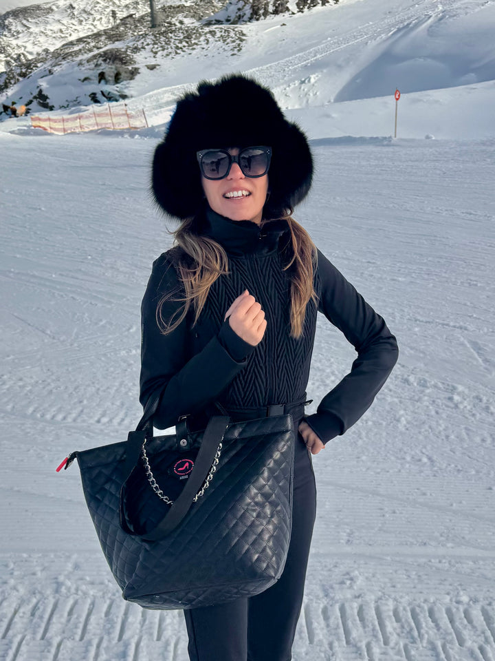Woman in black and fur hat holding black caviar leather KATE All-time Favourites Small Tote Bag on snowy slope.
