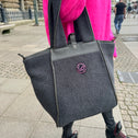 Frau mit Handtasche, kleiner grauer Teddy-Shopper mit zwei Henkeln, Reißverschluss und rosa Logo vorne