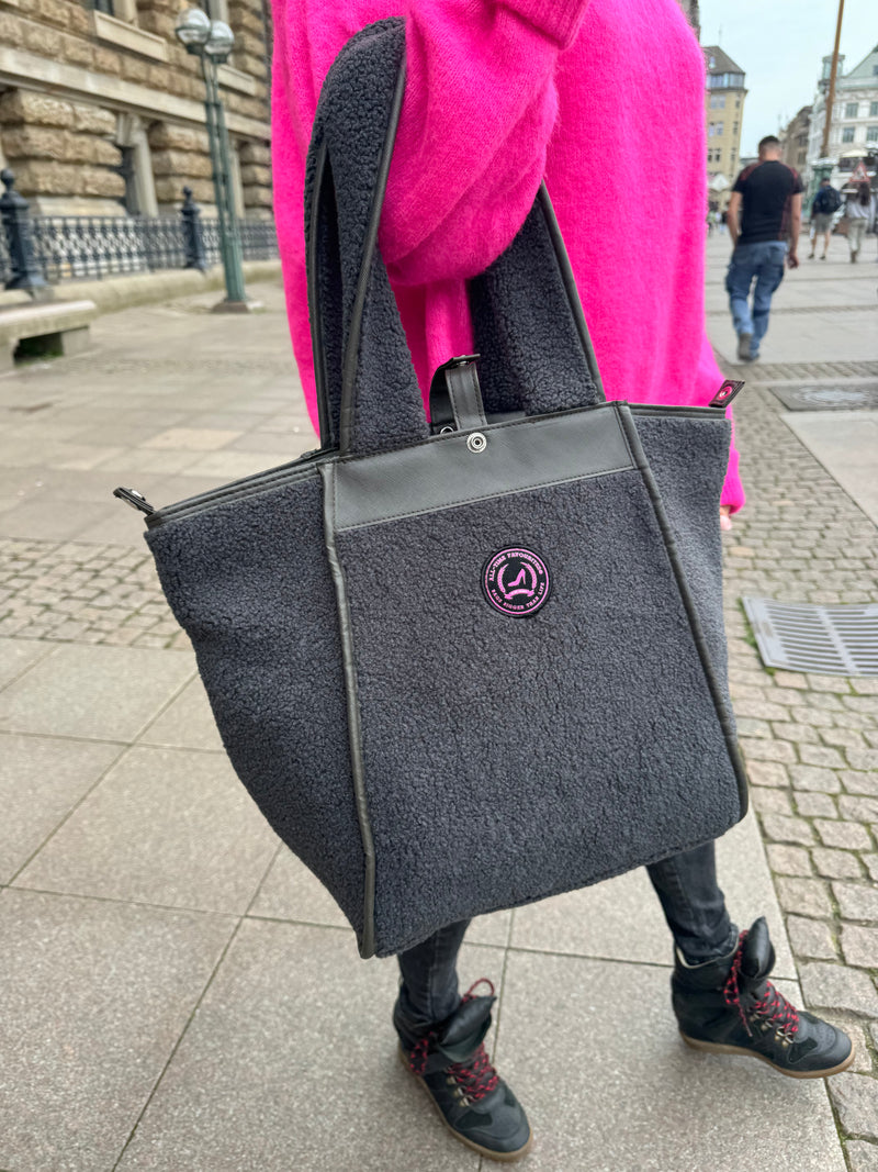 Frau mit Handtasche, kleiner grauer Teddy-Shopper mit zwei Henkeln, Reißverschluss und rosa Logo vorne