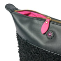 Black faux shearling clutch with gold zipper and pink accents, IMAN brand, close-up view.