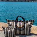 Striped handbags on a stone ledge with a scenic background of water and mountains.