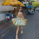 Woman walking through a street in Thailand carrying a large gold python print tote bag over her shoulder