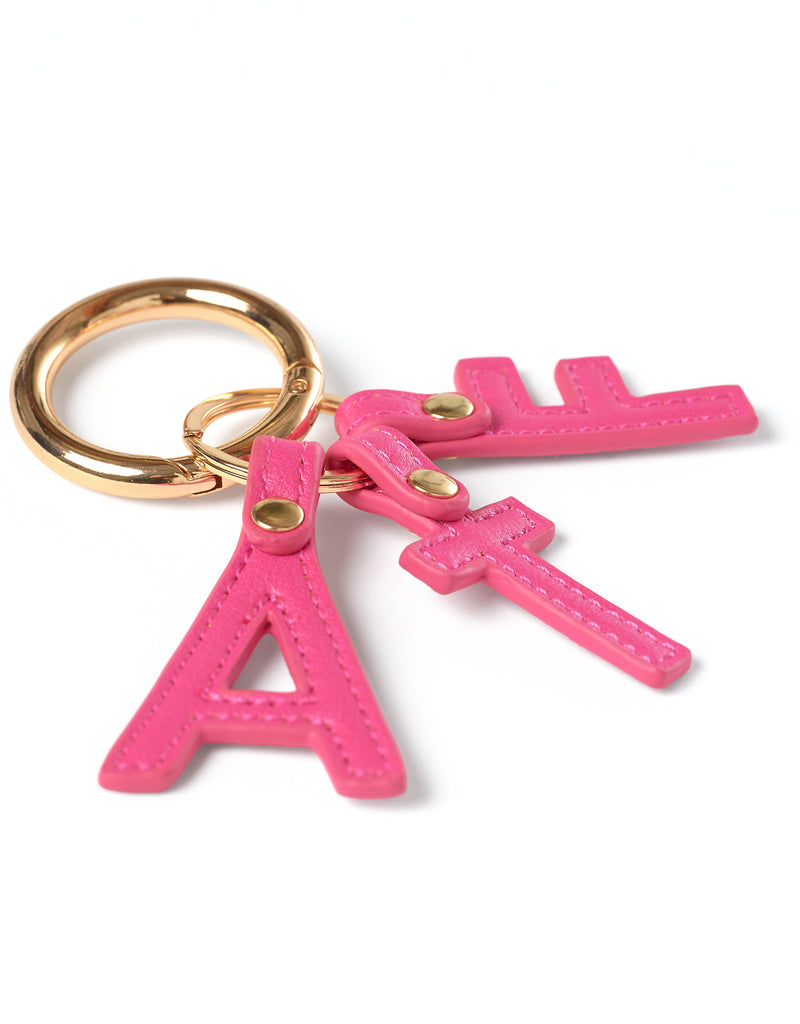 Pink letter 'A', 'T' and 'F' keychain with gold ring on a white background
