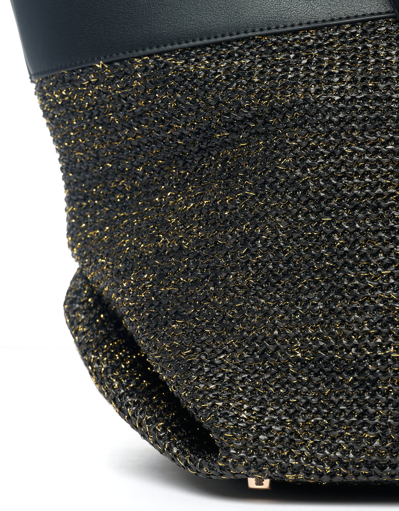 Bottom of black tote bag with protective metal studs and black raffia with gold thread.
