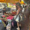 Woman shopping at a street market carrying a large gold metallic tote bag