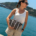 Woman holding a black & white striped All-time Favourites clutch by the water