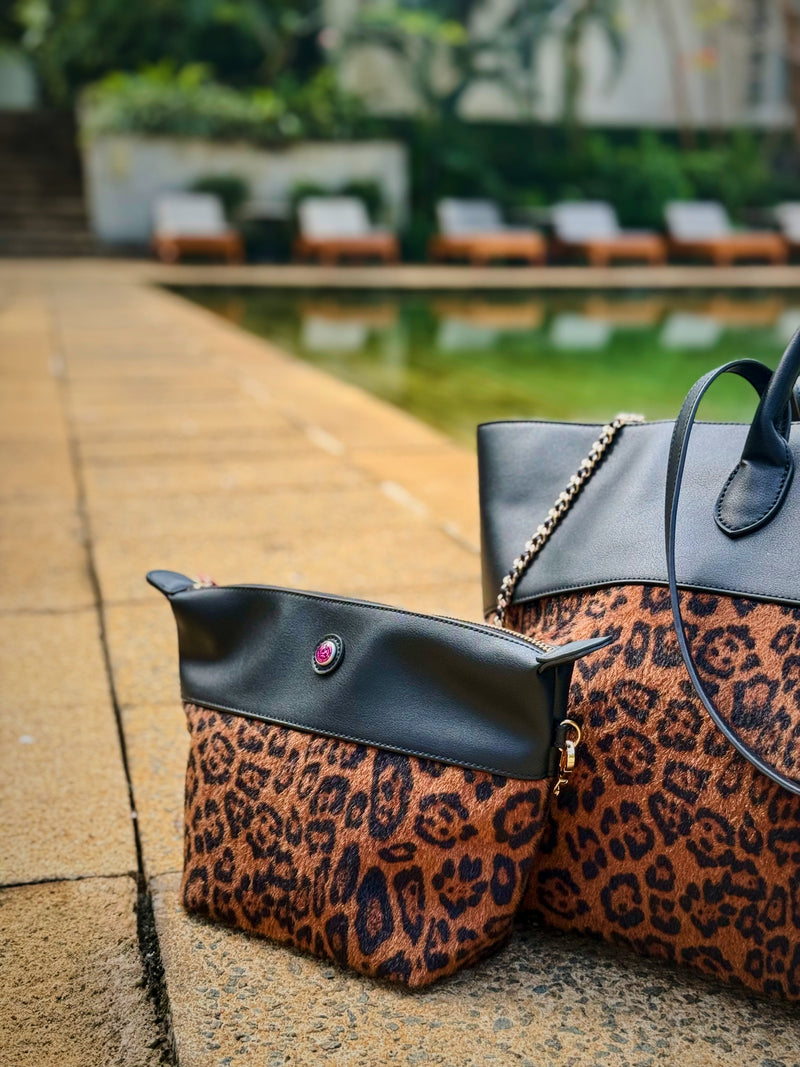 Leopard print handbag with matching bag-in-bag on a stone surface with a blurred garden and pool in the background