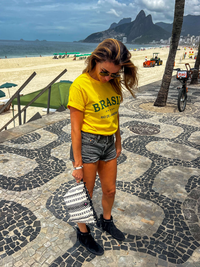 Woman holding black and white Rio toiletry bag on the boulevard in Rio de Janeiro