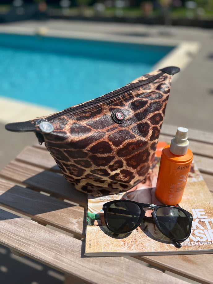 toiletry bag with zipper leopard print used by poolside with sunglasses and sunscreen